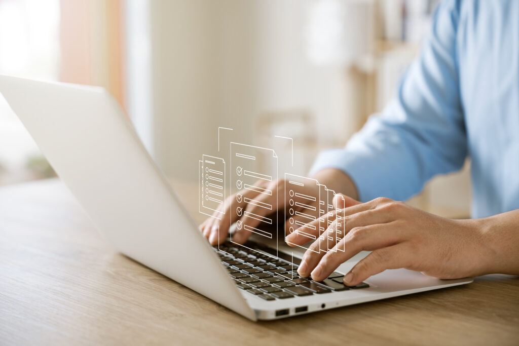 Person (m/w/d) arbeitet am Laptop, digitale Dokumente erscheinen als virtuelle Symbole – Symbolbild für strukturierte, papierlose Prozesse